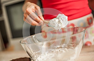 Adult woman whipping cream with whisk in glass bowl