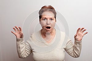 Adult woman on a white background in a light sweater. Emotions