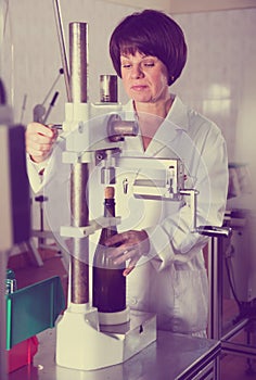 Adult worker corking wine bottles with machine