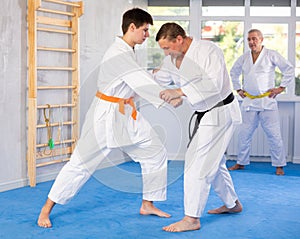 Adult and young men training judo fight