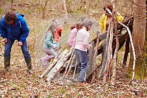 Adults And Children Building Camp At Outdoor Activity Centre