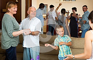 Adults and children dancing at a party at home