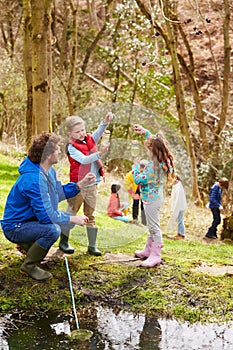 Adults And Children Exploring Pond At Activity Centre