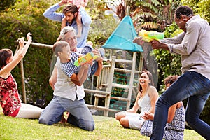 Adults and kids having fun with water pistols in a garden