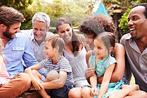 Adults and kids sitting on the grass in a garden photo