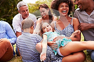 Adults and kids sitting on the grass in a garden