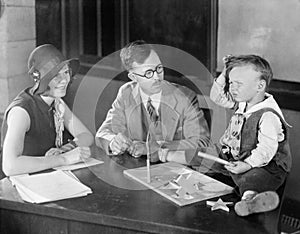 Adults testing little boy doing puzzle