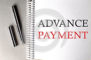 ADVANCE PAYMENT text on a notebook with pen on grey background