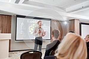 Advanced level education. Young male speaker in suit with headset and laser pointer giving a talk at business meeting