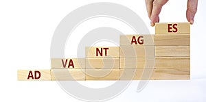 Advantages symbol. Wooden blocks stacking as step stair on white background, copy space. Businessman hand. Word `advantages`.