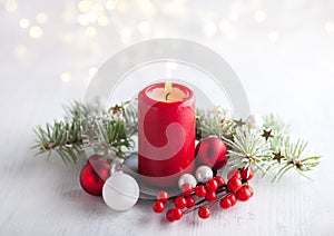Advent candle with  Christmas decoration and lights of garland   on white  rustic wooden  table.  Selective focus.  Focus on candl