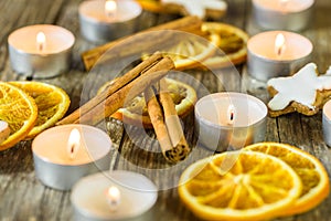 Advent candle lights, star shape biscuits, cinnamon and orange slices on wooden table
