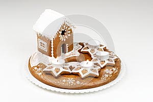 Advent candlestick with two lighted candles and christmas homemade gingerbread house on white background