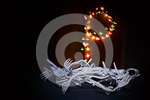 Advent crown from disposable forks with blurred Christmas lights.