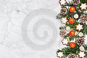 Advent decoration with four burning candles, conifer tree branches, pine cones, cinnamon star cookies on marble