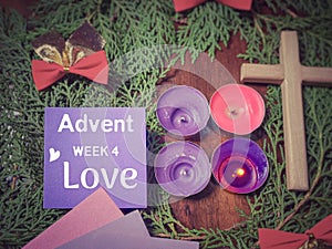 Advent week 4 love text on paper with the purple candle lit background. Advent Season Concept.