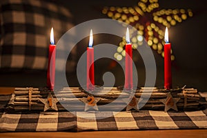 Advent wood sticks candle holder with silver stars with numbers 1,2,3,4. Four burning red candles. Christmas decoration