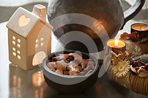 Advent wreath with burning candle and delicious homemade gingerbread cookies in small bowl of black pottery