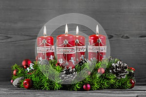 Advent wreath or crown with four red candles on wooden background.