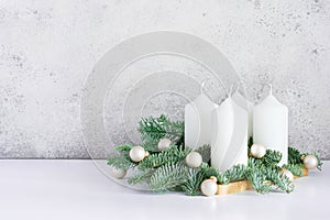 Advent wreath with four white candles, fir branches on a light gray background. Sunday December.