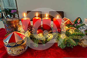 An advents wreath with four burning candles and some biscuits, time before the christmas eve.