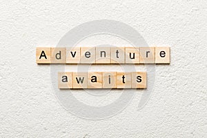 Adventure awaits word written on wood block. Adventure awaits text on cement table for your desing, concept