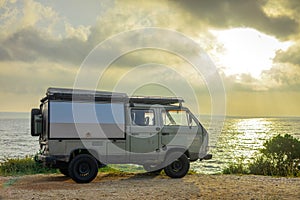 Adventure camper van or campmobile parked next to a nice beach at sunrise on a picturesque island of Losinj. Road trip with an old