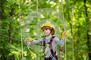 Adventure climbing high wire park. Cute school child boy enjoying a sunny day in a climbing adventure activity park