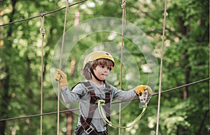 Adventure climbing high wire park. Cute school child boy enjoying a sunny day in a climbing adventure activity park