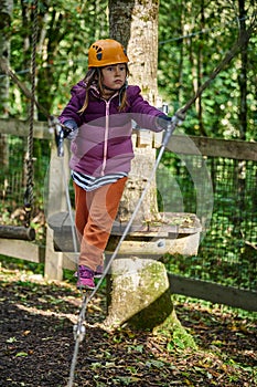 adventure climbing high wire park - kids on course in mountain helmet and safety equipment
