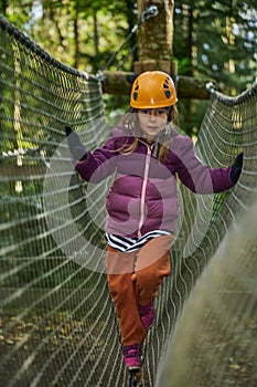 adventure climbing high wire park - kids on course in mountain helmet and safety equipment