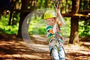 Adventure climbing high wire park - little child on course in mountain helmet and safety equipment
