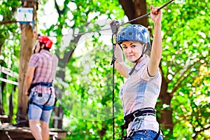 Adventure climbing high wire park - people on course in mountain helmet and safety equipment