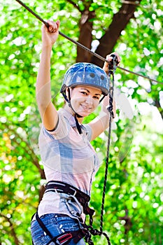 Adventure climbing high wire park - people on course in mountain helmet and safety equipment