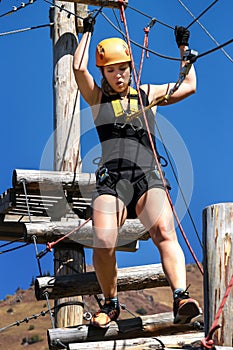 Adventure climbing rope park - a young woman in protective gear passes the track on a rope simulator. training mountaineers in the