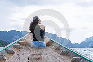 Adventure lifestyle vacationer relax concept. Traveler young woman holding own hair while sitting on long tail boat floating