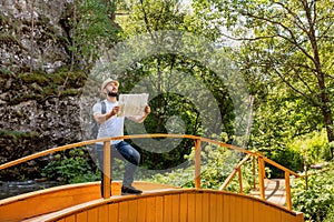 Adventure man with map and backpack on mountain in sun day. Bearded man tourist in mountain read map photo