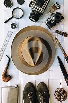 Adventure planning flat lay. Travel vintage gear on map. Including film camera, hat, knife, loupe, compass. Exploring, hiking
