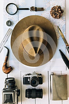 Adventure planning flat lay. Travel vintage gear on map. Including film camera, hat, knife, loupe, compass. Exploring, hiking