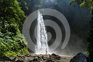 Adventure seeker standing near the beautiful jungle waterfall