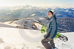 Adventure to winter sport. Snowboarder man hiking at mountain