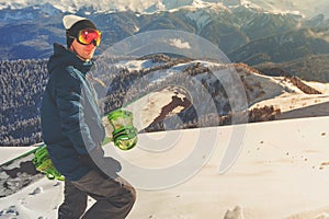 Adventure to winter sport. Snowboarder man hiking at mountain