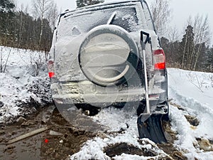 Adventure travel concept background. A 4x4 SUV stuck in mud and snow. Problems of car ownership in winter.