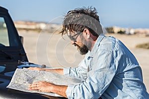 Adventure travel lifestyle - bearded adult man looking paper map to plnt the trip and journey - people choosing destination -