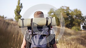 Adventure, travel, tourism, hike and people concept. Backside traking view of friends walking with backpacks by hills