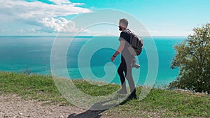 Adventure, travel, tourism, hike and people concept - hiking man with backpack looking at sea or ocean in summer