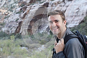 Adventure, travel, tourism, hike and people concept - man carrying black backpack hiking in the desert rocky mountains