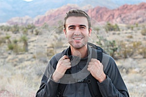 Adventure, travel, tourism, hike and people concept - man holding his backpack hiking in the desert rocky mountains