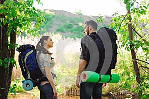 Adventure, travel, tourism, hike and people concept - smiling couple with backpacks outdoors.