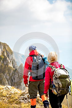 Adventure, travel, tourism, hike and people concept - smiling couple walking with backpacks outdoors